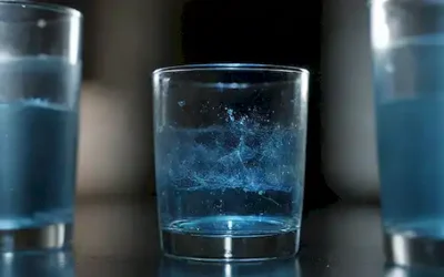 Un vaso lleno de agua rodeado de un campo magnético representado por líneas azules brillantes