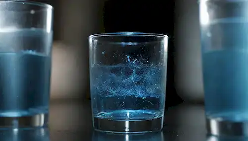 Un vaso lleno de agua rodeado de un campo magnético representado por líneas azules brillantes