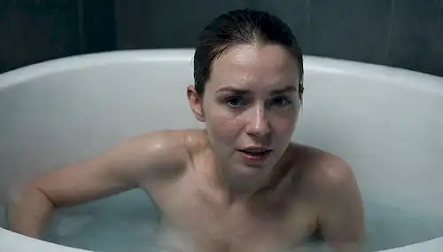 Persona en una bañera rodeada de agua helada, expresión facial mostrando incomodidad y dolor, las manos atornilladas de los bordes de la bañera para el soporte, los dedos que se vuelven azules del frío, el vapor que se eleva del agua, fondo oscuro y sombrío para transmitir sentido de incomodidad