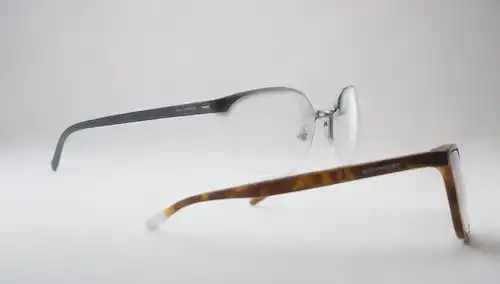 ilustración 3D de dos pares de gafas con diferentes formas y ángulos de lente, un par con una separación clara entre dos lentes de prescripción, otro con una transición gradual, tanto en un fondo blanco con sutil sombra e iluminación, rodeado de formas abstractas para sugerir un sentido de profundidad y complejidad