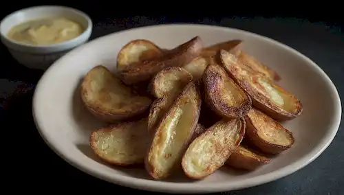 Un plato con pieles de patata cocidas, un tenedor y un cuchillo cerca, con sutil afeitado para indicar la textura; un resplandor débil y lenceroso que rodea el plato; un fondo oscuro para resaltar el punto focal; un sentido del malestar transportado a través de la composición