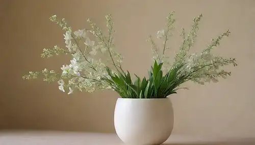 hojas verdes exuberantes, delicadas flores blancas, algunas ramas florecientes, enfoque suave, luz natural cálida, sombras sutiles, un jarrón decorativo o una olla, un color de fondo tranquilo, elegante sencillez, mínima mezcla, arreglo visualmente atractiva