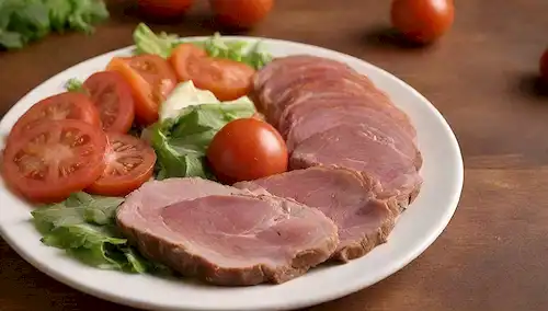 Un plato con carnes cortadas, rojas y blancas, en una composición de estilo gradiente, con verduras como tomates, cebollas y lechuga; un fondo de colores cálidos como naranja, amarillo y marrón para representar tonos terrenales; posiblemente una tabla de corte o un entorno rústico; presentación sencilla y apetitosa
