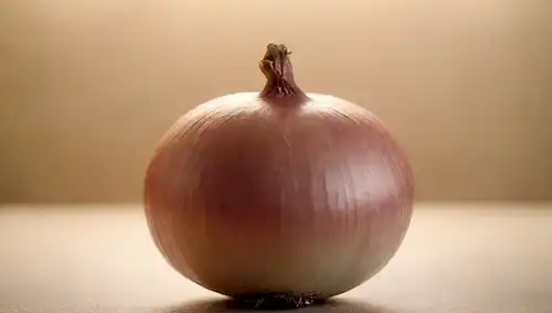 Una fotografía de tono cálido que muestra un disparo de cerca de una cebolla jugosa, sus capas ligeramente levantadas para revelar la textura interior translúcida; rodeada de luz suave, brillante y un fondo sutil, evocando sentimientos de calma y serenidad