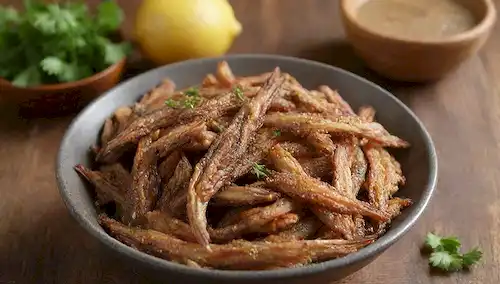 Una toma de cerca de anchoas fritas crujientes enclavadas en un tazón lleno de vinagre cursi
