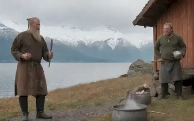 siglo IX Guerrero vikingo de pie frente a un longhouse de madera