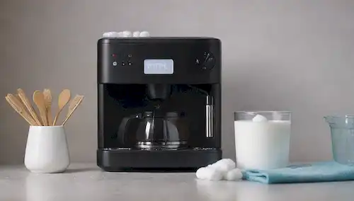ilustración 3D de una máquina de café con piezas extraíbles como cesta de filtro, bandeja de goteo y depósito de agua, rodeado de pequeñas herramientas de limpieza como swabs de algodón, cepillo y tela, con sutiles toques de vapor que suben desde la parte superior para transmitir frescura y calidez, con un fondo limpio y moderno