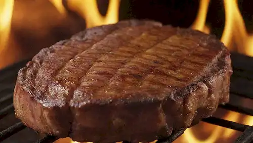 Una costilla de cerdo, dorado, deslumbrante en una parrilla; carne jugosa que cae del hueso; bordes tiernos y caramelizados; piel crujiente; tonos rústicos y terrosos; iluminación caliente; aromas sabrosos que se mueven hacia arriba; presentación apetitosa; detalles de desprendimiento