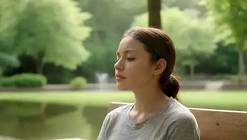 Persona sentada tranquilamente en un banco de parques, ojos cerrados, respirando profundamente, rodeada de exuberante vegetación, con una característica de agua tranquila en el fondo, suave iluminación natural, suave brisa suave