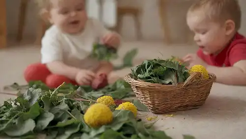 3-5 niños de 1 a 3 años jugando con juguetes, verduras (spinnaches, verdes de remolacha y hojas de león) dispersos alrededor, unas pocas hojas sopladas de una cesta o placa cercana, enfoque suave, colores brillantes, composición caprichosa