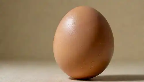 Un acercamiento de un huevo marrón con grietas, mostrando la yema blanca cremosa rodeada de finas membranas translúcidas, contra un fondo neutro con sombras sutiles, destacando la textura y las variaciones de color