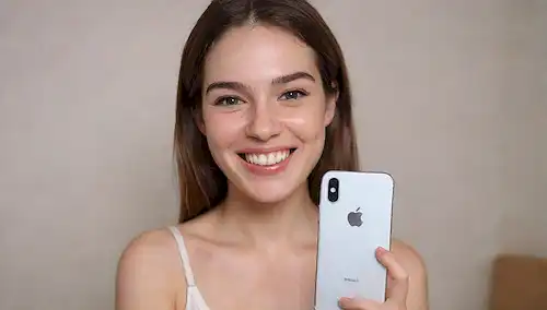 iPhone en la mano, mujer sonriendo, fondo blanco, sutil gradiente, reflexión débil, pantalla del smartphone iluminado, icónico logotipo de Apple prominente, suave efecto borrón, iluminación cálida, props simples, composición limpia