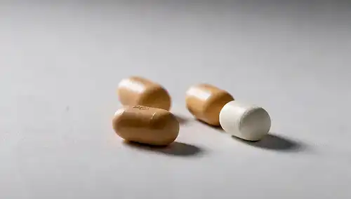 3 pastillas en una fila sobre un fondo blanco, las píldoras están ligeramente decoloradas, algunas con residuos o manchas en la superficie, una píldora tiene una grieta, todas con grados de desgaste diferentes