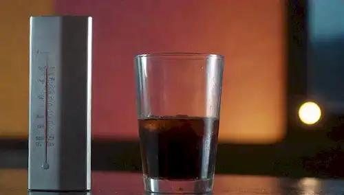 Una persona que lleva ropa oscura de pie frente a un termómetro, sudor goteando de su frente, con un fondo de color brillante contrastante, un vaso de bebida fría en la mesa cercana, y un toque de ambiente sombrío para crear una escena ambigua