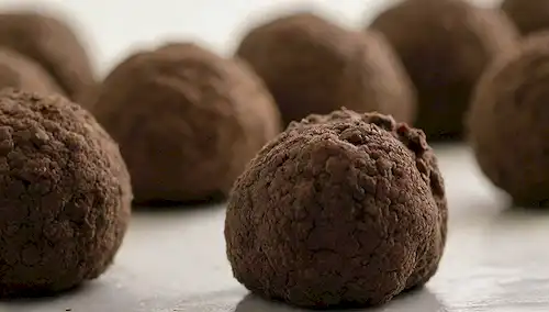 disparo de cerca de algunas trufas en una superficie blanca, con luz natural suave, tonos terrenales, y detalles intrincados