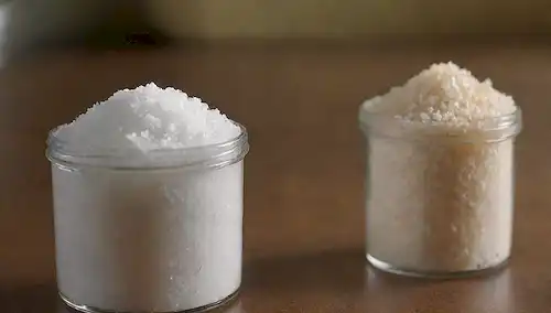 cristales de azúcar 3D con un formato de pantalla dividida, comparando dos contenedores llenos de gránulos blancos (maltitol), con un fondo débil insinuando un entorno de cocina o despensa, y aspectos sutiles que sugieren un tono científico o educativo