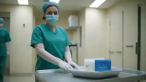 Un entorno médico estéril, una enfermera, una bandeja de instrumentos quirúrgicos, un dispensador de la mano sanitizante, toallitas antisépticas, una botella de solución desinfectante, una máscara quirúrgica, un par de guantes, una caja de guante médico, un corredor hospitalario