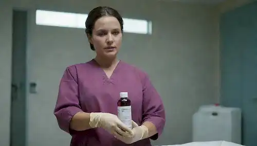 Un trabajador sanitario con guantes y vestido, sosteniendo una botella de solución de yodo povido con un gotero, un modelo de piel de herida o cortada en el fondo, entorno hospitalario, entorno estéril, equipo médico, enfermera o figura médica