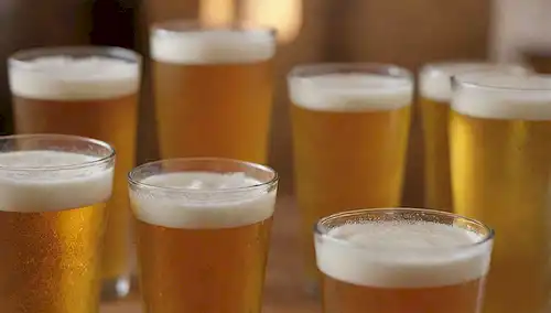 6-paquete, conos de aro, líquido novato, cabeza de espuma, vidrio nublado, equipo de elaboración, fondo de madera o industrial, color dorado o ámbar, ambiente rústico, entorno inspirado en la cervecería, tema de la cerveza artesanal