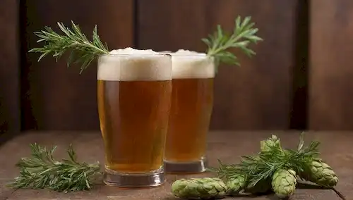 2-3 púas, un vaso lleno de cerveza nublada, un fondo de madera o rústico, iluminación cálida, algunas ramitas de hierbas frescas