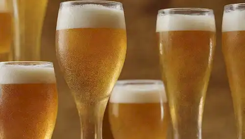 9 cristalería vierte con diferentes cantidades de espuma de cerveza, dispuesta en un collage o patrón de mosaico, con cada vertido que muestra un tono diferente de color amarillo dorado a naranja