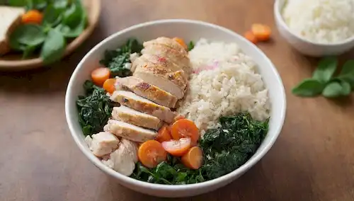 Un cuenco cálido y acogedor lleno de pollo jugoso, arroz ahumado y espinacas verde vibrante, adornado con verduras crujientes y una rocia de hierbas frescas en una mesa de madera rústica, contra un fondo borroso de enfoque suave, iluminado por la luz natural de arriba, con algunas hojas frescas y flores comestibles dispersas alrededor de los bordes