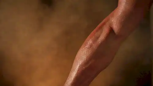 Primer plano de un brazo o pierna de personas con músculos rojos e inflamados, sombras sutiles, enfoque suave en el área afectada, fondo borroso para enfatizar la textura muscular, iluminación caliente para transmitir dolor y molestias, posiblemente algunas wisps sutiles de humo o vapor que suben de los músculos para simbolizar tensión y dolor