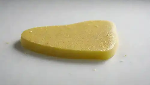 Una rodaja de hígado amarillo brillante y soleado en una superficie blanca, rodeada de pequeñas gotas de agua clorada, con unas pocas manchas de espuma verde claro, y un efecto de brillo sutil para resaltar su frescura, sentado sobre un fondo blanco claro y puro