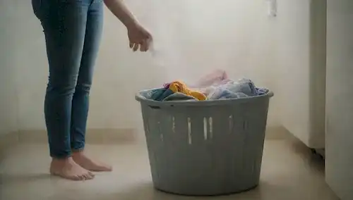 Una persona que sostiene una cesta de la ropa con una mezcla de ropa limpia y sucia