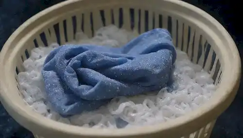 enredados en una malla o red, con mangueras de jabón y agua salpicando alrededor, rodeado de fondo azul oscuro, tapa de la cesta de la colada abierta, ropa sucia derramada