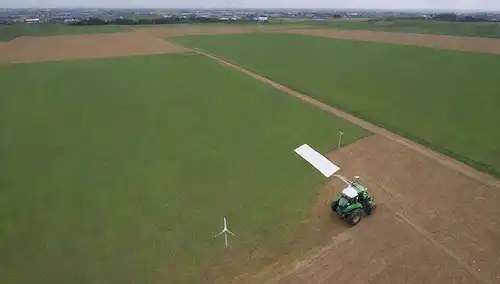 tierras agrícolas con equipos agrícolas de precisión, invernaderos, drones que vuelan sobre la tierra, paneles solares sobre cobertizos, sensores de suelo y estaciones de monitoreo, cultivos que crecen en hileras, un tractor que afloja la tierra, un agricultor inspecciona un cultivo, una turbina eólica generando electricidad, un plato satélite que recibe señales de órbita