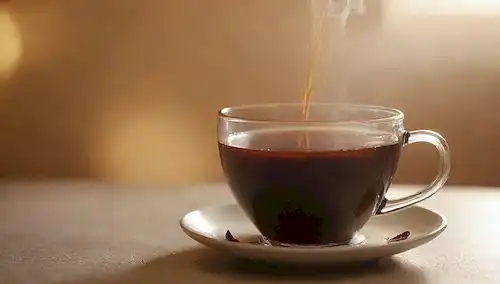 Una taza de vapor de té negro con un toque sutil en su superficie, rodeada de una cálida y acogedora iluminación ambiente, con unas pocas hojas sueltas dispersas alrededor del borde, contra un fondo suave y cremoso, con unos ligeros toques dorados, evocando un sentido de comodidad y relajación